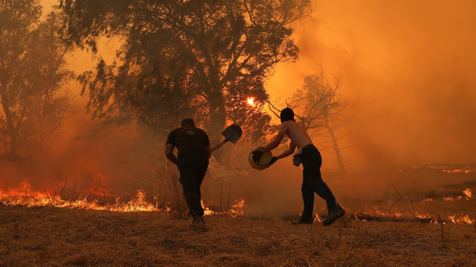 Rauch und Flammen steigen auf, während Feuerwehrteams einen Waldbrand nahe Athen bekämpfen