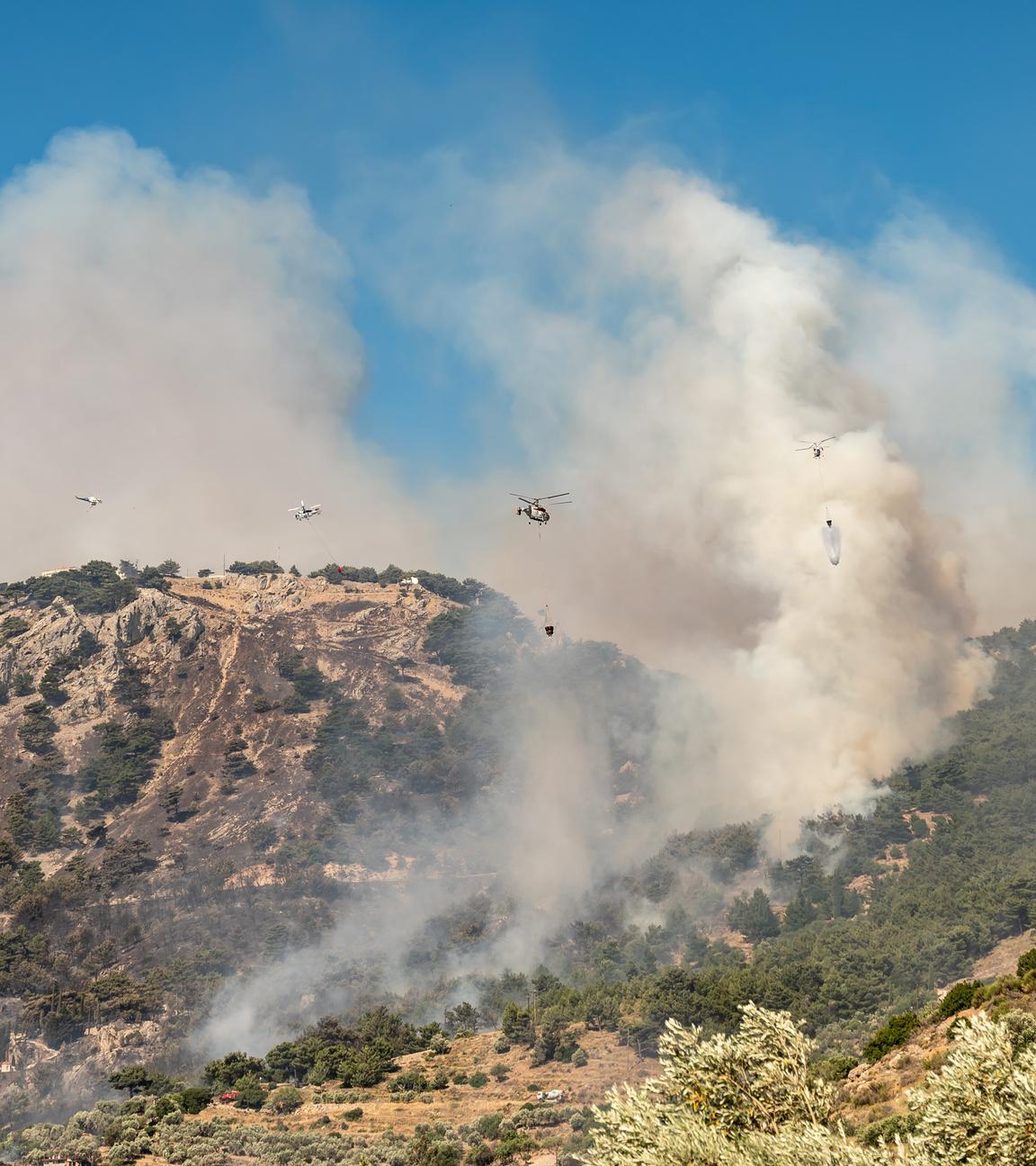 Rauch steigt auf aus einem Wald auf der griechischen Insel Chios, Löschhubschrauber versuchen, das Feuer unter Kontrolle zu bringen.