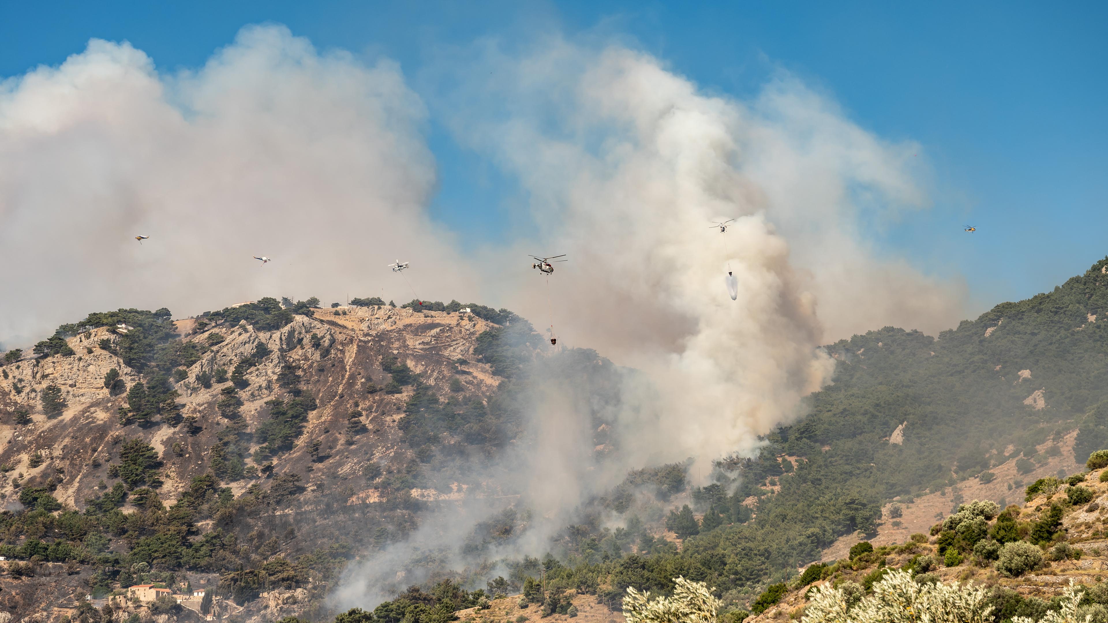 Rauch steigt auf aus einem Wald auf der griechischen Insel Chios, Löschhubschrauber versuchen, das Feuer unter Kontrolle zu bringen.
