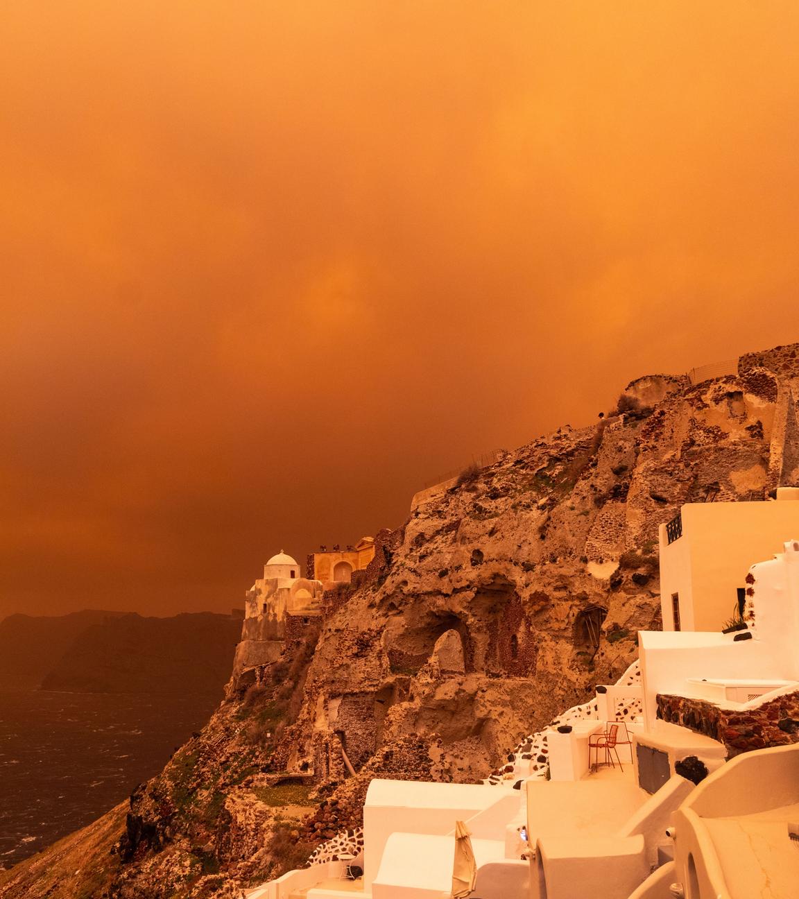 Ein kräftiger Sturm trägt Sand aus Afrika über die Insel Santorini und färbt den Himmel orangerot ein.