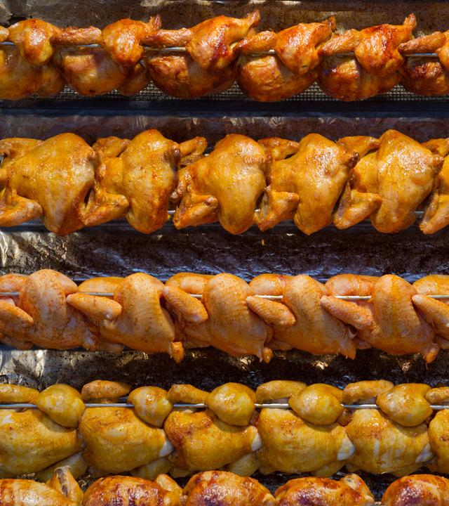 Mehrere Reihen Grillhähnchen am Grill.