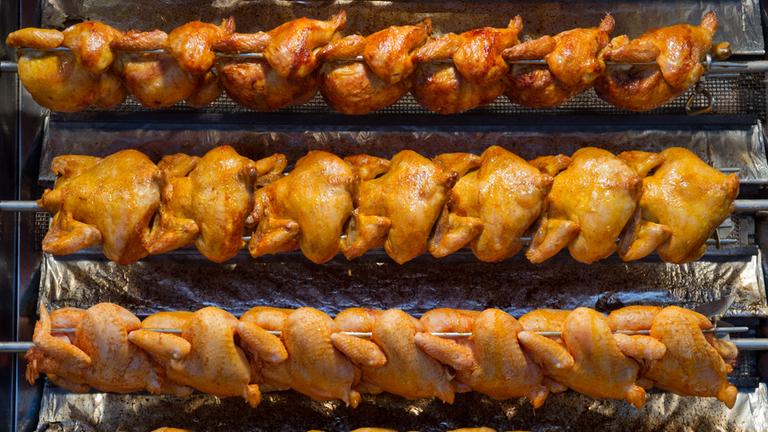 Mehrere Reihen Grillhähnchen am Grill.