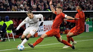 Im DFB-Pokal-Achtelfinale am 03.12.2024 geht Bayers Grimaldo gegen Bayern Kimmich und Olise in den Kampf um den Ball. 