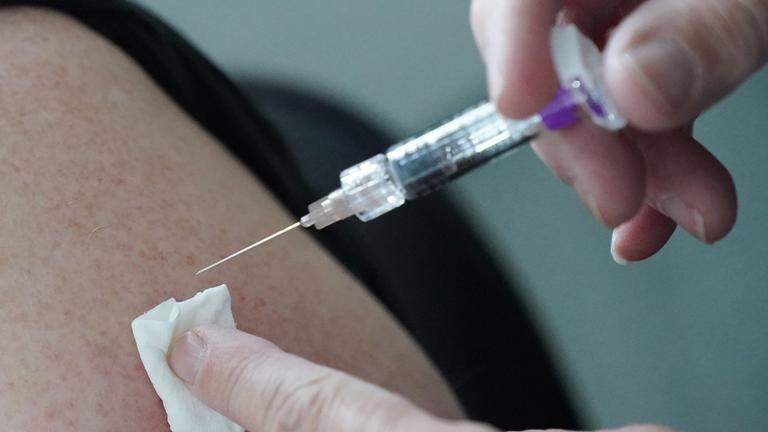 Eine Ärztin impft eine Person mit einem Impfstoff gegen Grippe