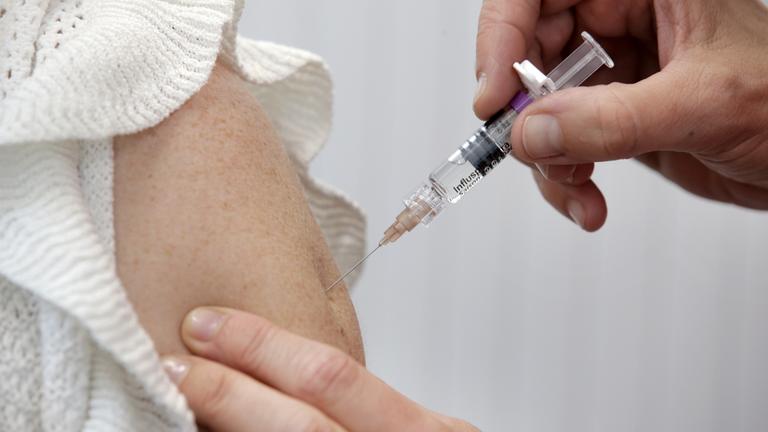 Ein Ärztin impft eine Patientin gegen Virusgrippe.