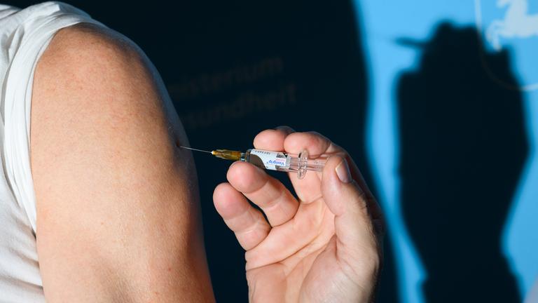 Ein Arzt impft einen Mann bei einem Pressetermin zur Grippeschutzimpfung im niedersächsischen Gesundheitsministerium mit dem Grippeimpfstoff Vaxigrip