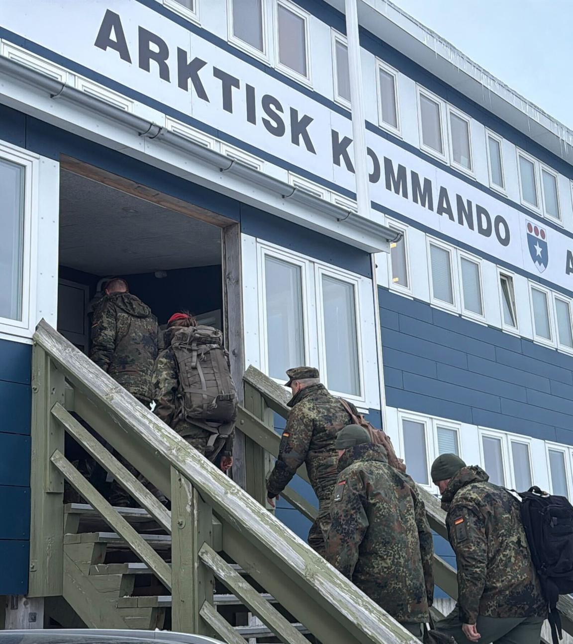 Mehrere Bundeswehr-Soldaten gehen die Treppe zu einem Gebäude mit der Aufschrift "Arktisk Kommando - Arctic Command" hinauf. Im Hintergrund schneebedeckte Berge.