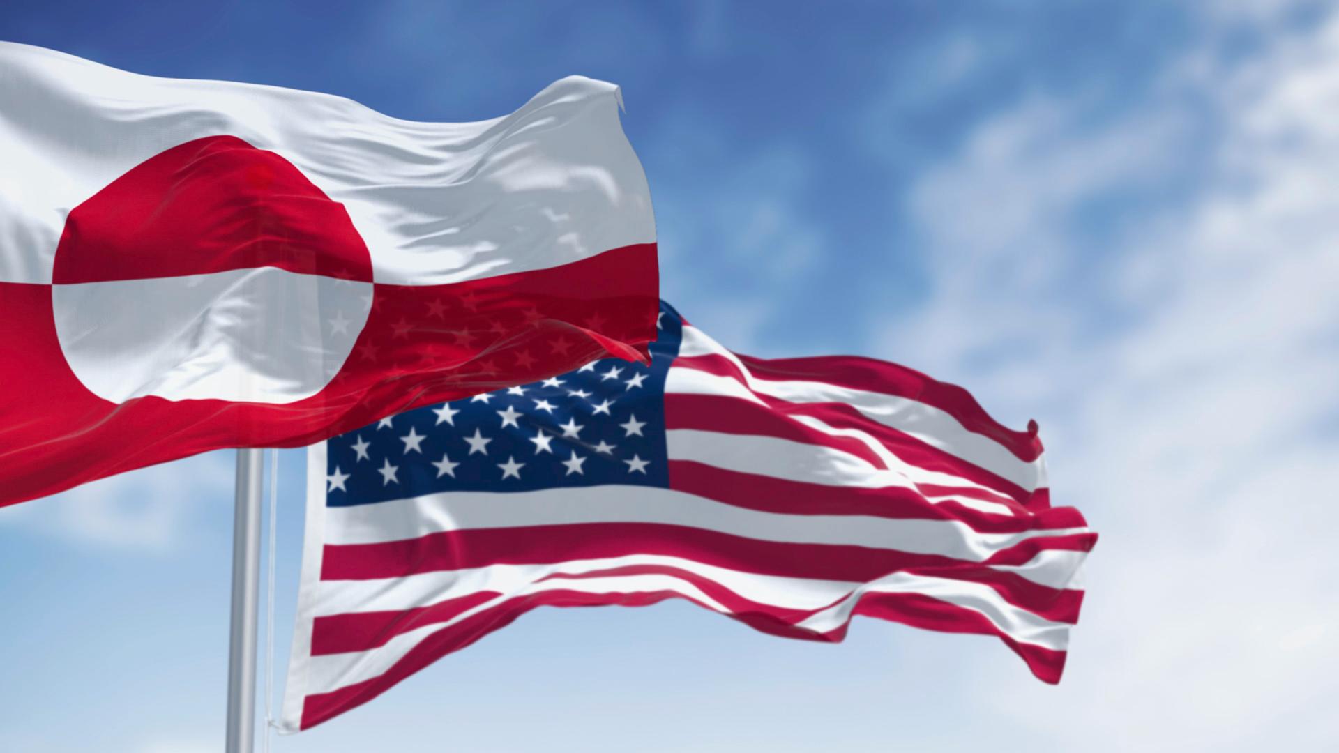 Die Flaggen von Grönland und den USA wehen an einem klaren Tag im Wind - Bildmontage