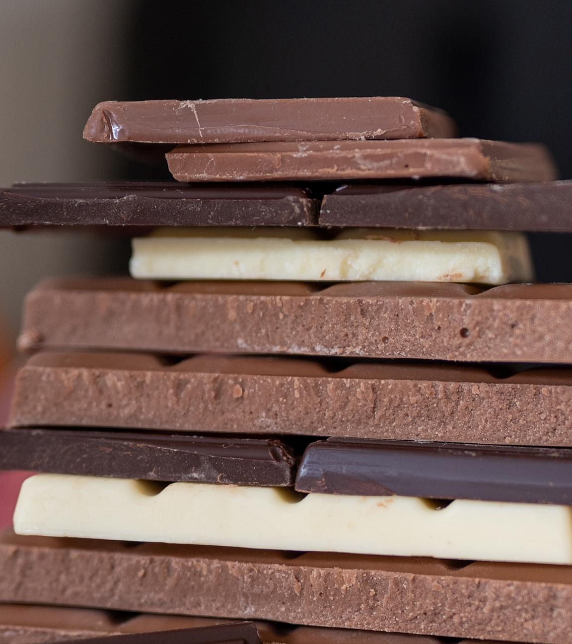 Mehrere Stücke verschiedener Sorten Schokolade liegen aufeinander.