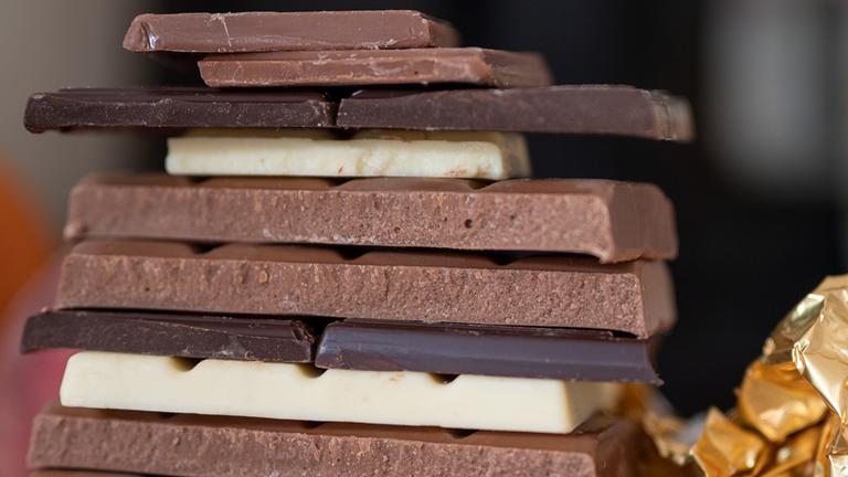 Mehrere Stücke verschiedener Sorten Schokolade liegen aufeinander.