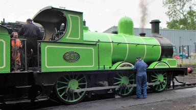 Drei Männer in Oberalls arbeiten an der Lokomotive 957 alias „Der Grüne Drache“.