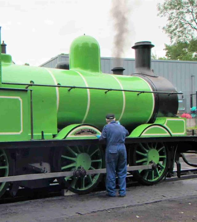Drei Männer in Oberalls arbeiten an der Lokomotive 957 alias „Der Grüne Drache“.
