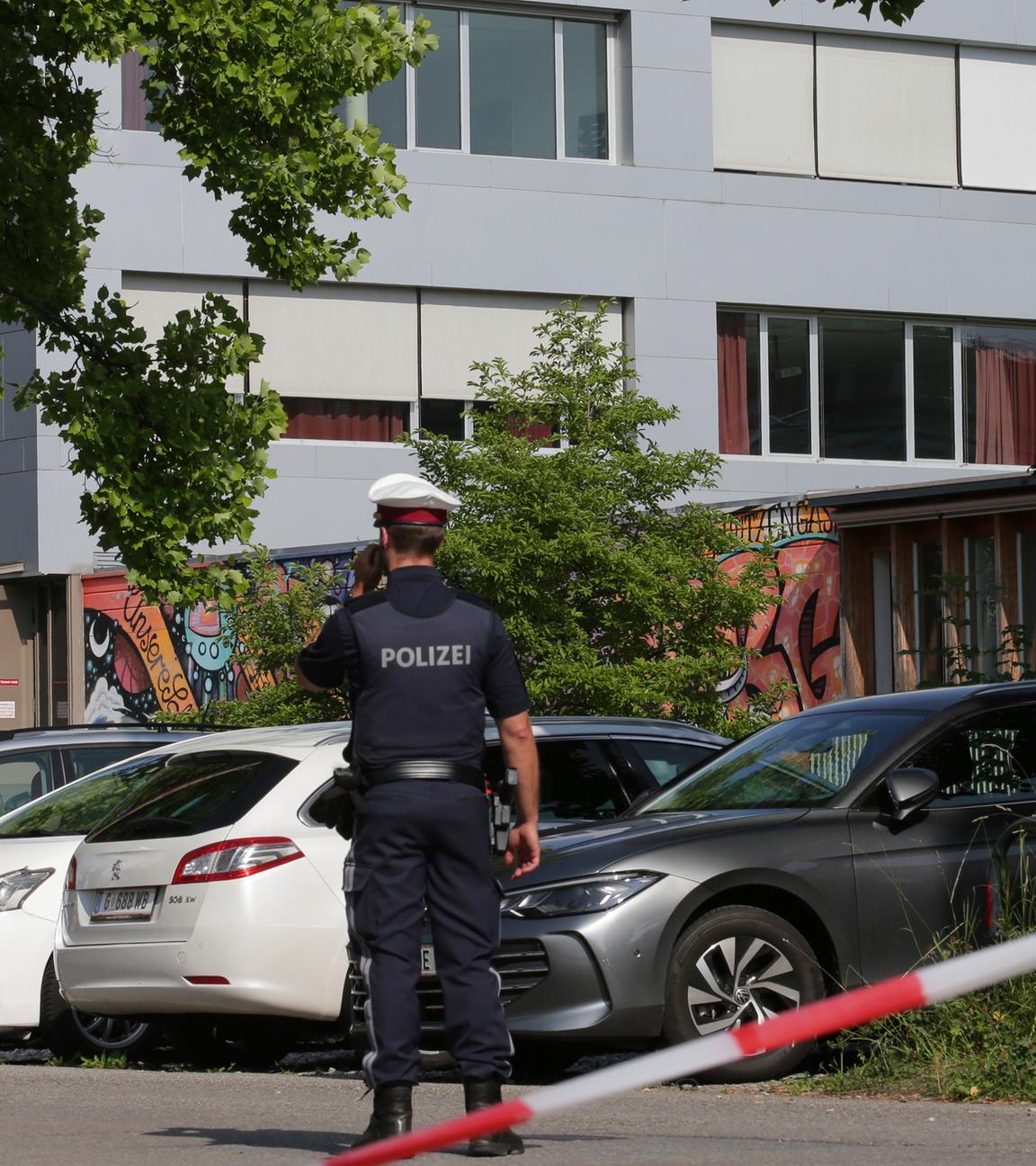 Österreich, Graz: Ein Polizeibeamter telefoniert vor dem Schulgebäude.