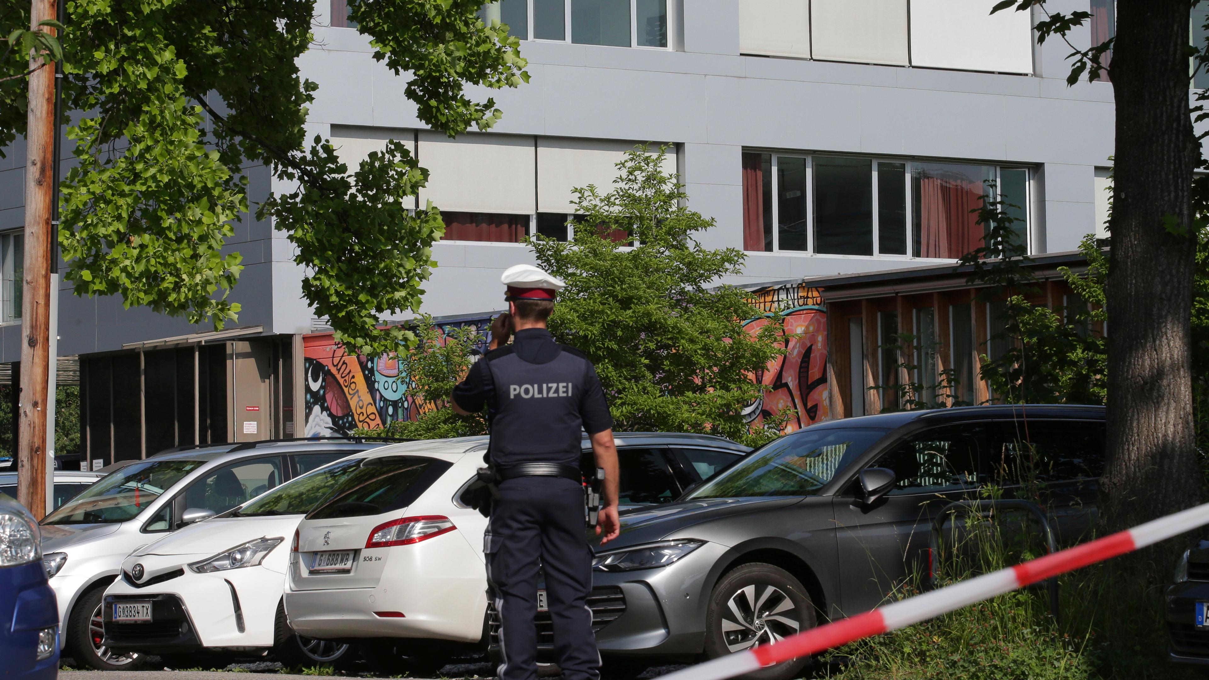 Österreich, Graz: Ein Polizeibeamter telefoniert vor dem Schulgebäude.
