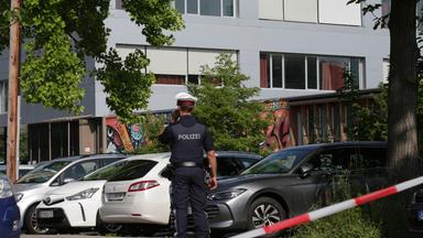 Österreich, Graz: Ein Polizeibeamter telefoniert vor dem Schulgebäude.