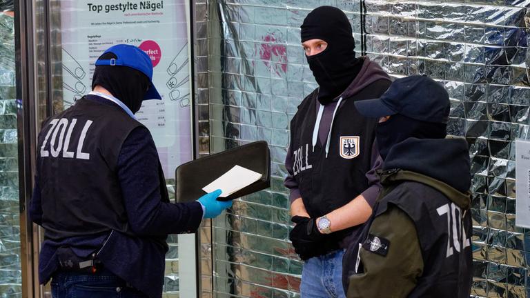 Zollbeamte stehen vor einem Nagelstudio in der Neumarktgalerie in der Innenstadt.