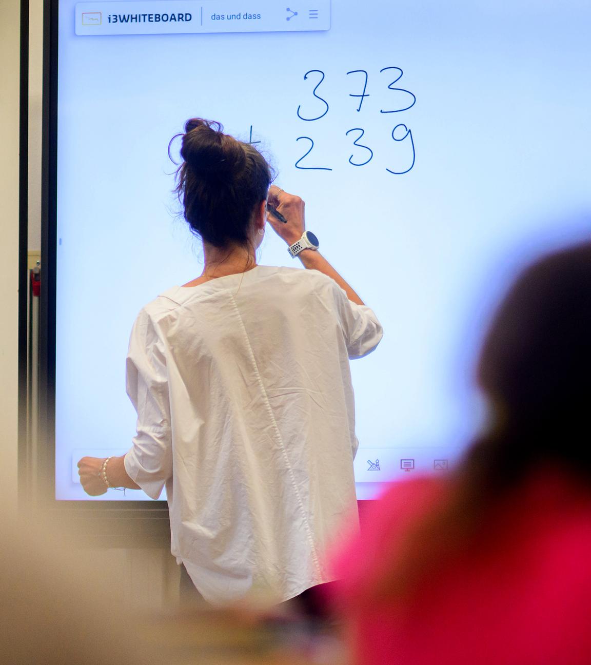 Ein Lehrerin schreibt eine Mathematikaufgabe auf eine digitale Schultafel im Klassenraum einer 4. Klasse einer Grundschule in der Region Hannover (Archivfoto)