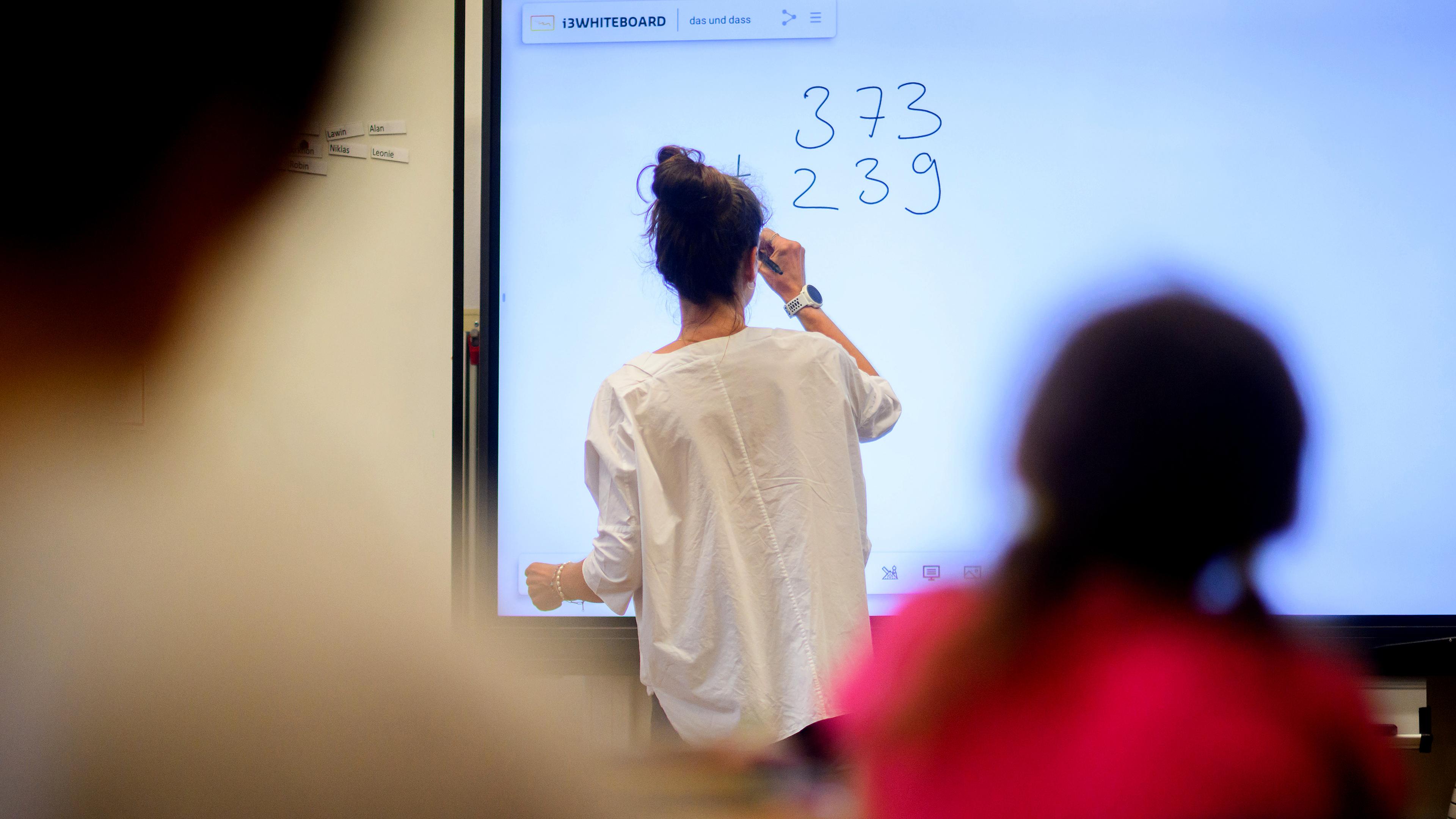 Ein Lehrerin schreibt eine Mathematikaufgabe auf eine digitale Schultafel im Klassenraum einer 4. Klasse einer Grundschule in der Region Hannover (Archivfoto)