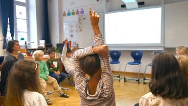 Grundschüler meldet sich im Unterricht
