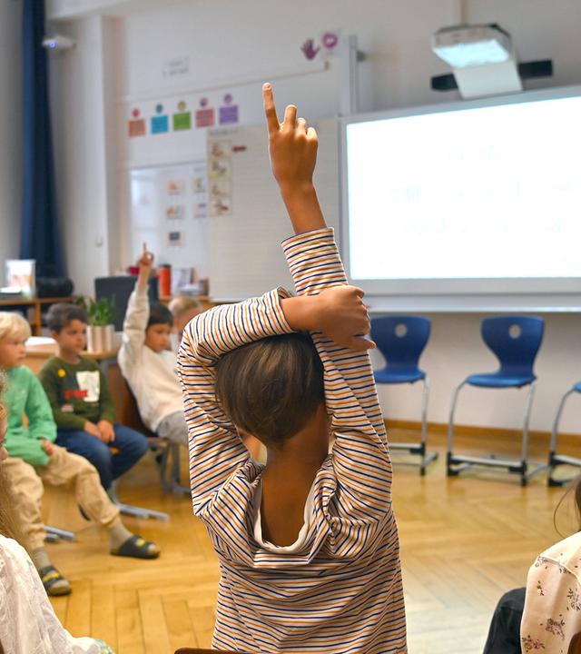 Grundschüler meldet sich im Unterricht