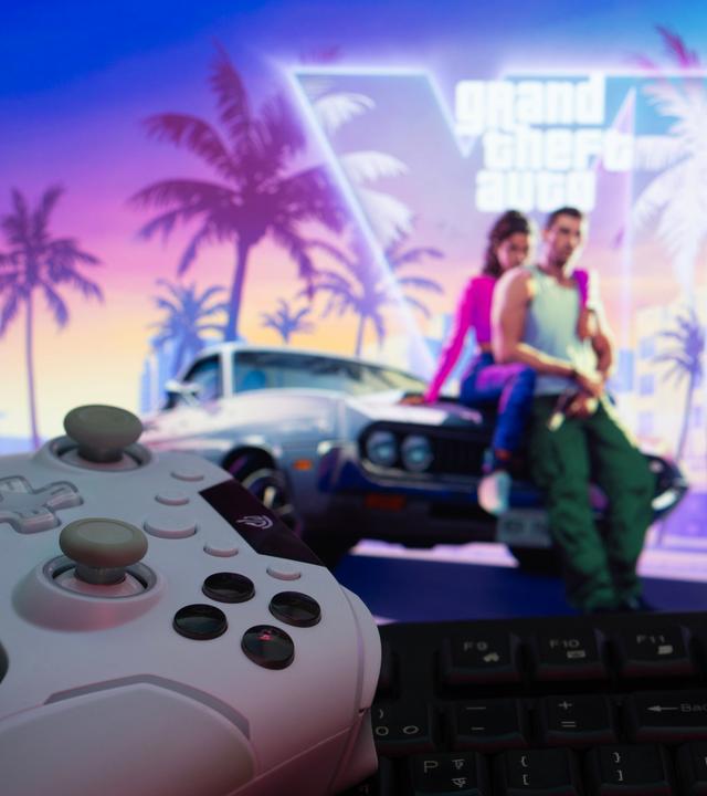 Eine Spielkonsole mit Gamepad und Tastatur vor einem Grand Theft Auto VI-Hintergrund auf einem Computermonitor. 