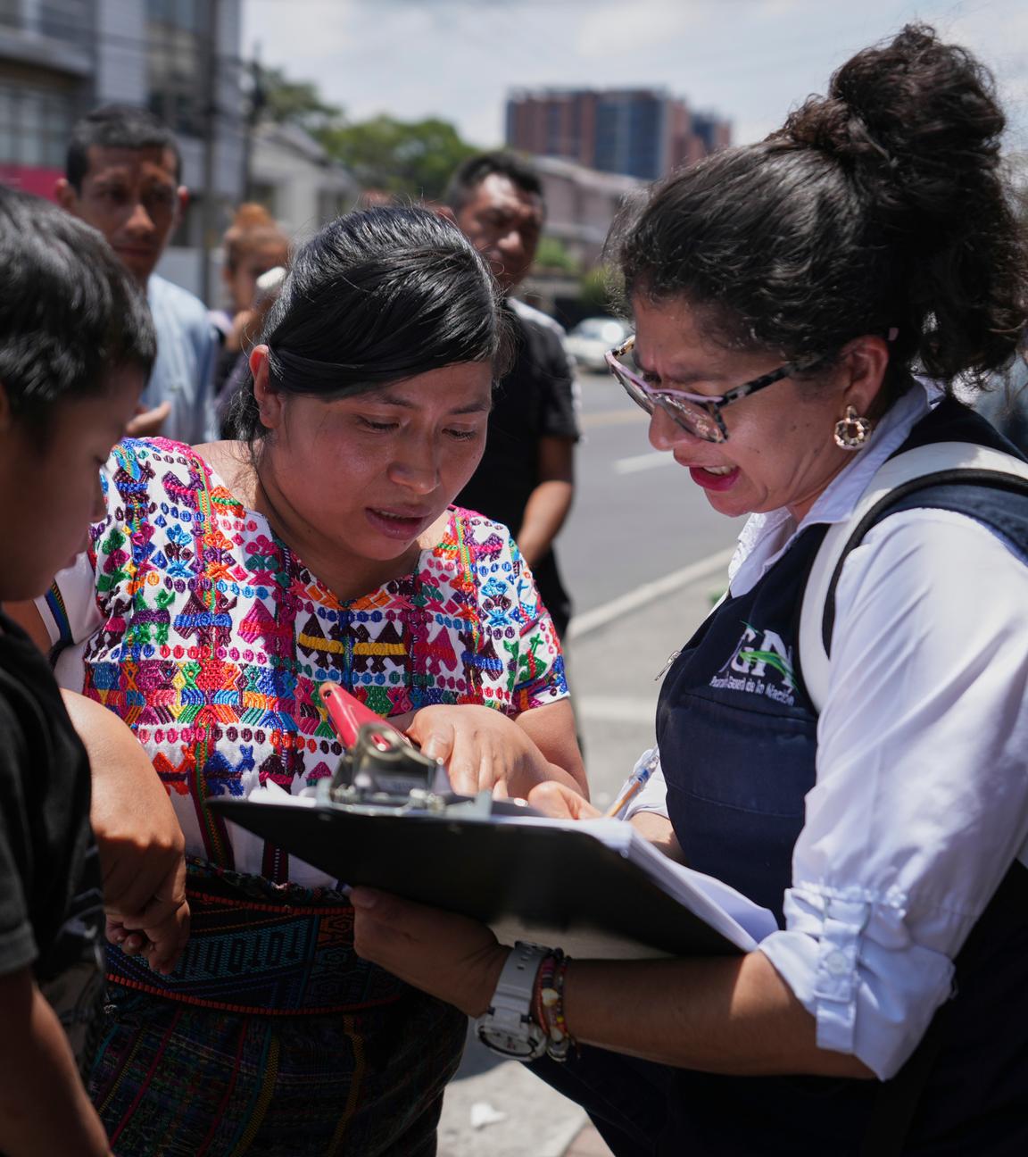 Eine Familienangehörige überprüft eine Namensliste von aus den USA abgeschobenen Migranten am Flughafen La Aurora in Guatemala Stadt.