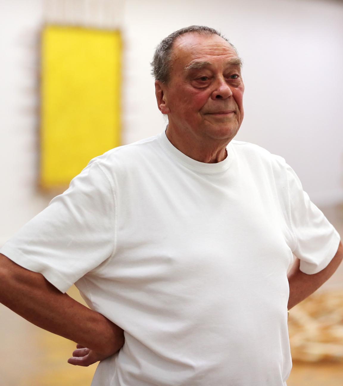 Guenther Uecker schaut zur Seite und lächelt, im Hintergrund eine Ausstellung