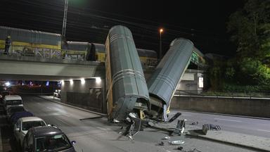 Zwei Waggons eines Güterzugs liegen auf einer Straße, nachdem sie von einer Brücke gestürzt sind.