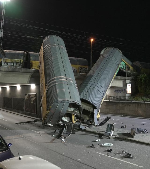 Zwei Waggons eines Güterzugs liegen auf einer Straße, nachdem sie von einer Brücke gestürzt sind.