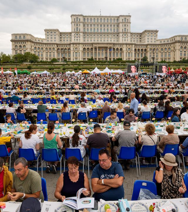Menschen sitzen an einem 5 Kilometer langen, aus recycelten Materialien gefertigten „Tisch der Einheit“ (Uniting Table) – im Rahmen einer Veranstaltung zur Aufstellung eines Guinness-Weltrekords und zur Spendensammlung für eine kinderpsychiatrische Einrichtung – vor dem aus der kommunistischen Ära stammenden Parlamentspalast in Bukarest, Rumänien, am Samstag, dem 12. September 2026.