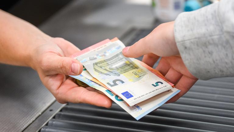 Eine Kassiererin gibt einer Kundin Geld an der Kasse eines Supermarktes.