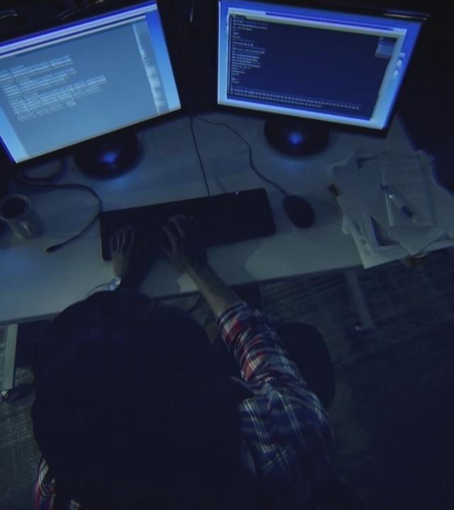 Zwielichtige Person (Hacker) tippt auf einer Computer-Tastatur rum