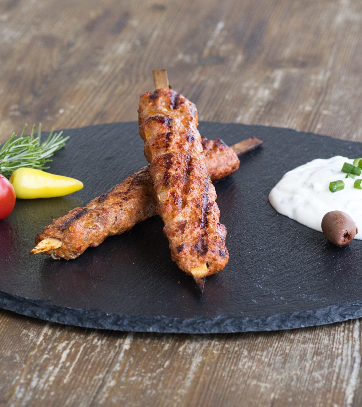 Hackspieße vom Grill mit Joghurt-Dip serviert auf einer Schieferplatte