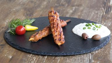 Hackspieße vom Grill mit Joghurt-Dip serviert auf einer Schieferplatte