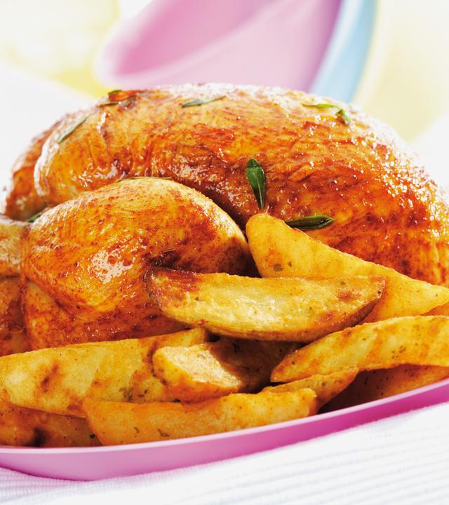 Ein halbes Brathähnchen und Pommes Frites liegen auf einem Teller.