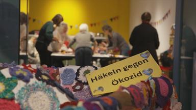 Omas beim Häkeln und gehäkelte Blüten im Vordergrund