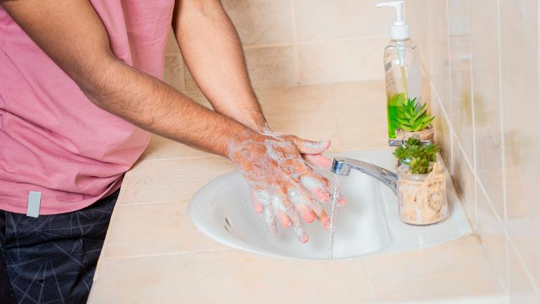 Eine Person wäscht ihre Hände gründlich mit Seife an einem Waschbecken.