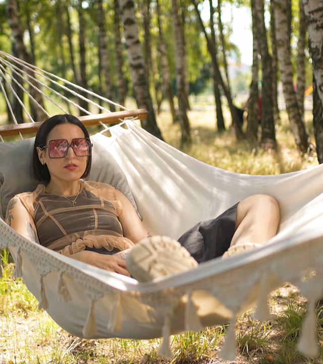 Frau mit Sonnenbrille liegt im Wald in einer Hängematte