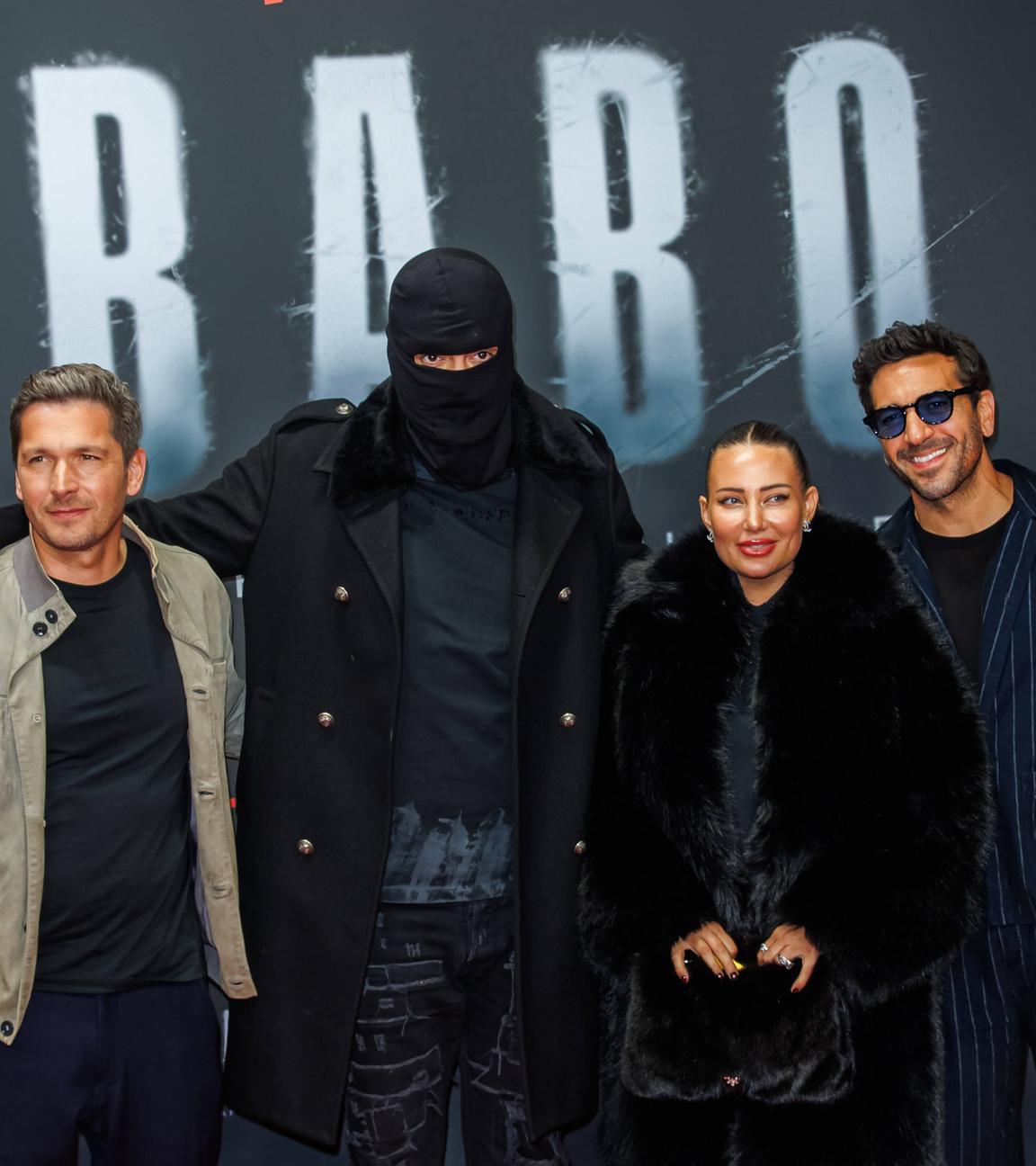 Auf dem Bild ist der Rapper Haftbefehl, seine Ehefrau und die Regiesseure seiner Dokumentation zu sehen. Sie alle posieren auf dem Roten Teppich der Premiere.