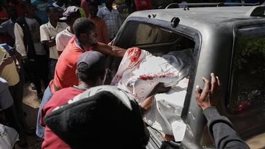 Mitarbeiter eines Leichenschauhauses bringen die Leichen von Opfern eines Bandenangriffs in Kenscoff bei Port-au-Prince in einen Krankenwagen.