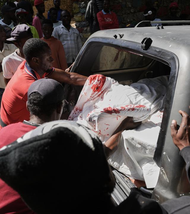 Mitarbeiter eines Leichenschauhauses bringen die Leichen von Opfern eines Bandenangriffs in Kenscoff bei Port-au-Prince in einen Krankenwagen.