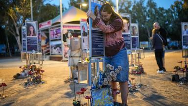Eine Frau umarmt eine Gedenktafel eines Opfers der Hamas.