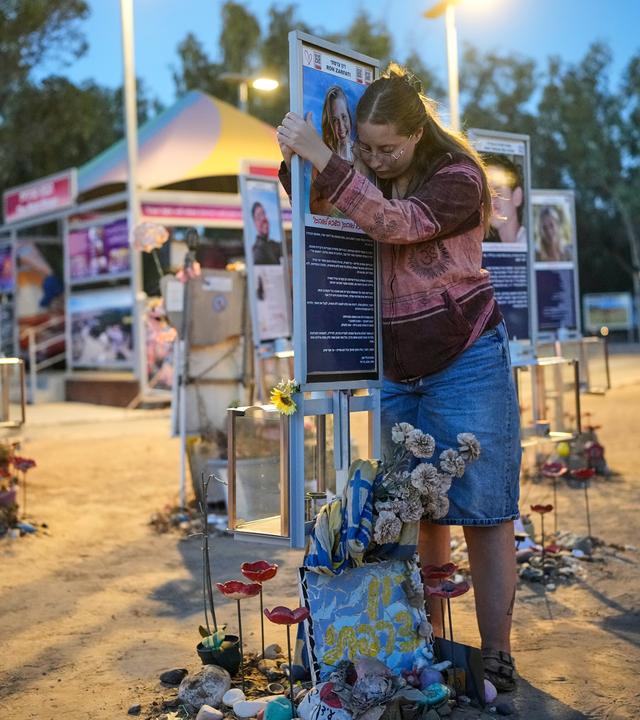 Eine Frau umarmt eine Gedenktafel eines Opfers der Hamas.