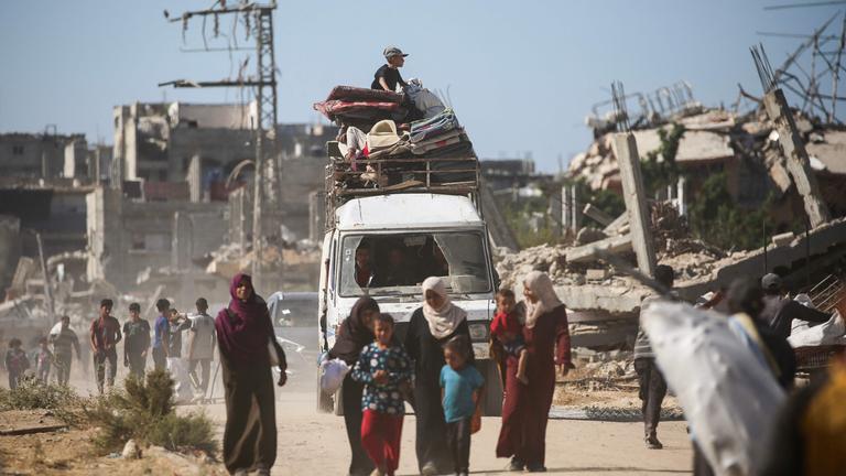 Ein Fahrzeug mit Beladung fährt die Straße entlang, darauf sitzt ein Kind