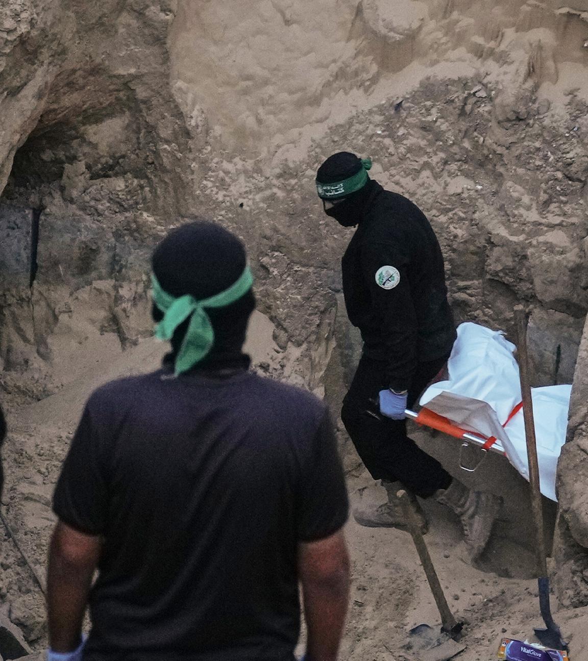 Hamas-Kämpfer tragen einen weißen Sack, vermutlich mit einer Leiche, bei der Suche nach Geisel-Überresten in Hamad City, Süder-Gazastreifen.