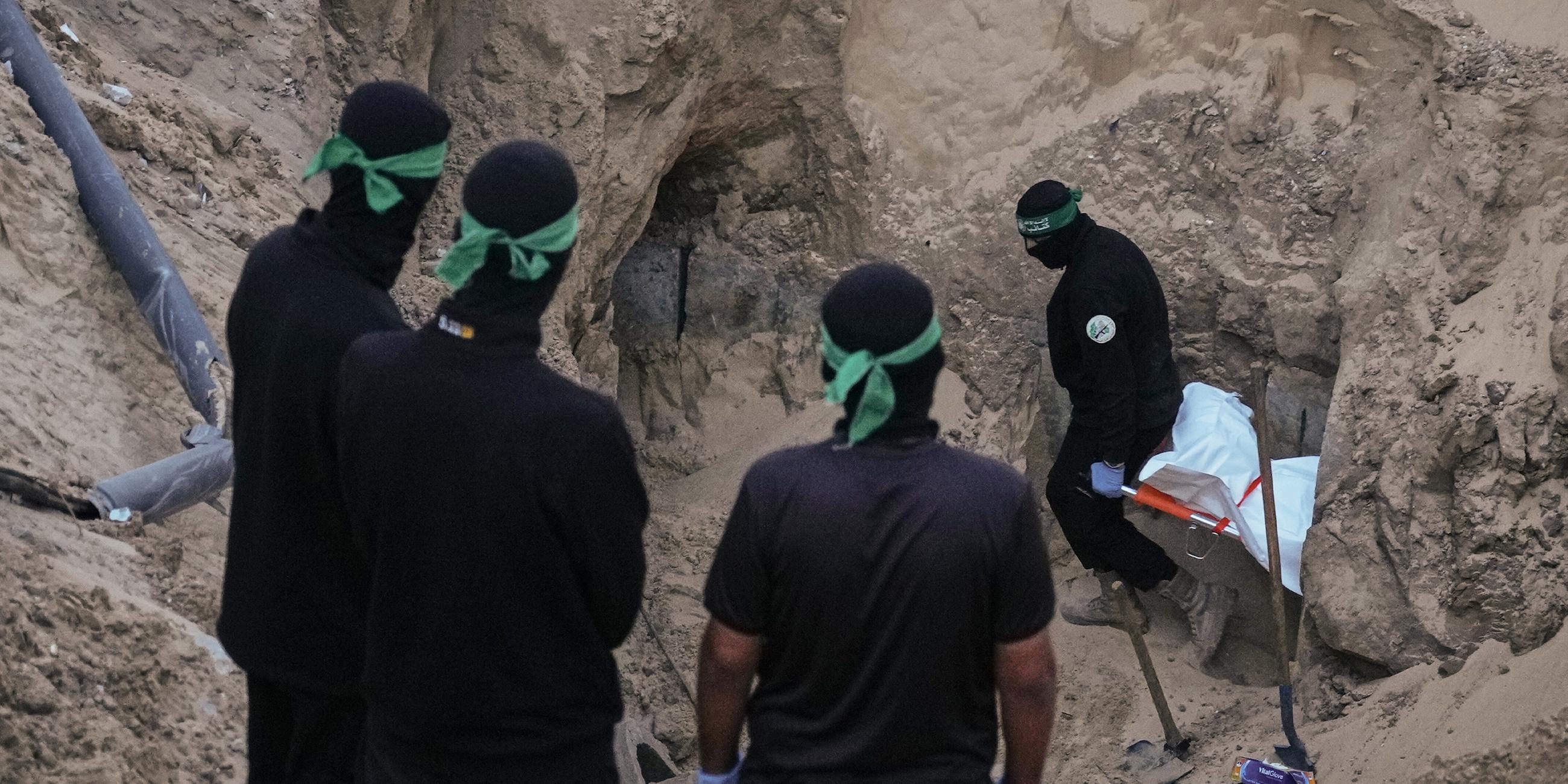 Hamas-Kämpfer tragen einen weißen Sack, vermutlich mit einer Leiche, bei der Suche nach Geisel-Überresten in Hamad City, Süder-Gazastreifen.