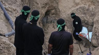 Hamas-Kämpfer tragen einen weißen Sack, vermutlich mit einer Leiche, bei der Suche nach Geisel-Überresten in Hamad City, Süder-Gazastreifen.