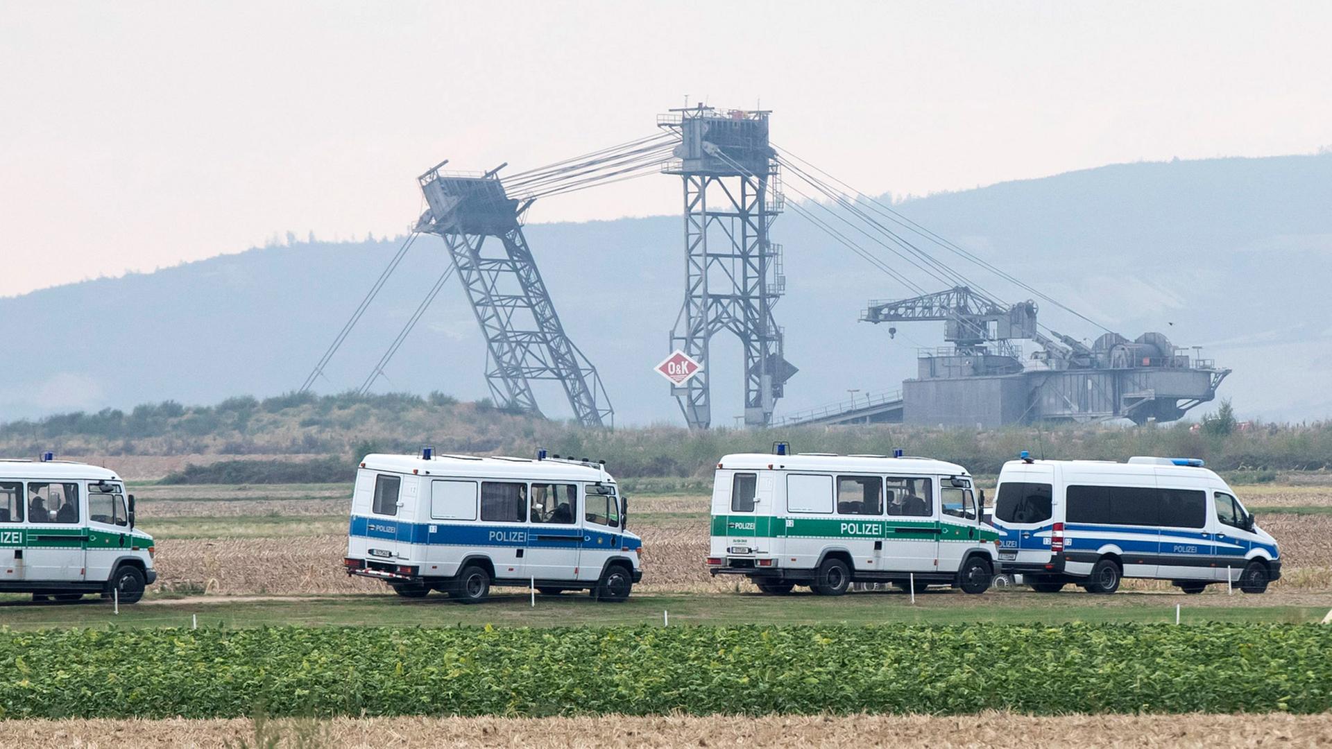 Polizeifahrzeuge stehen auf einem feld vor dem Tagebau Hambach
