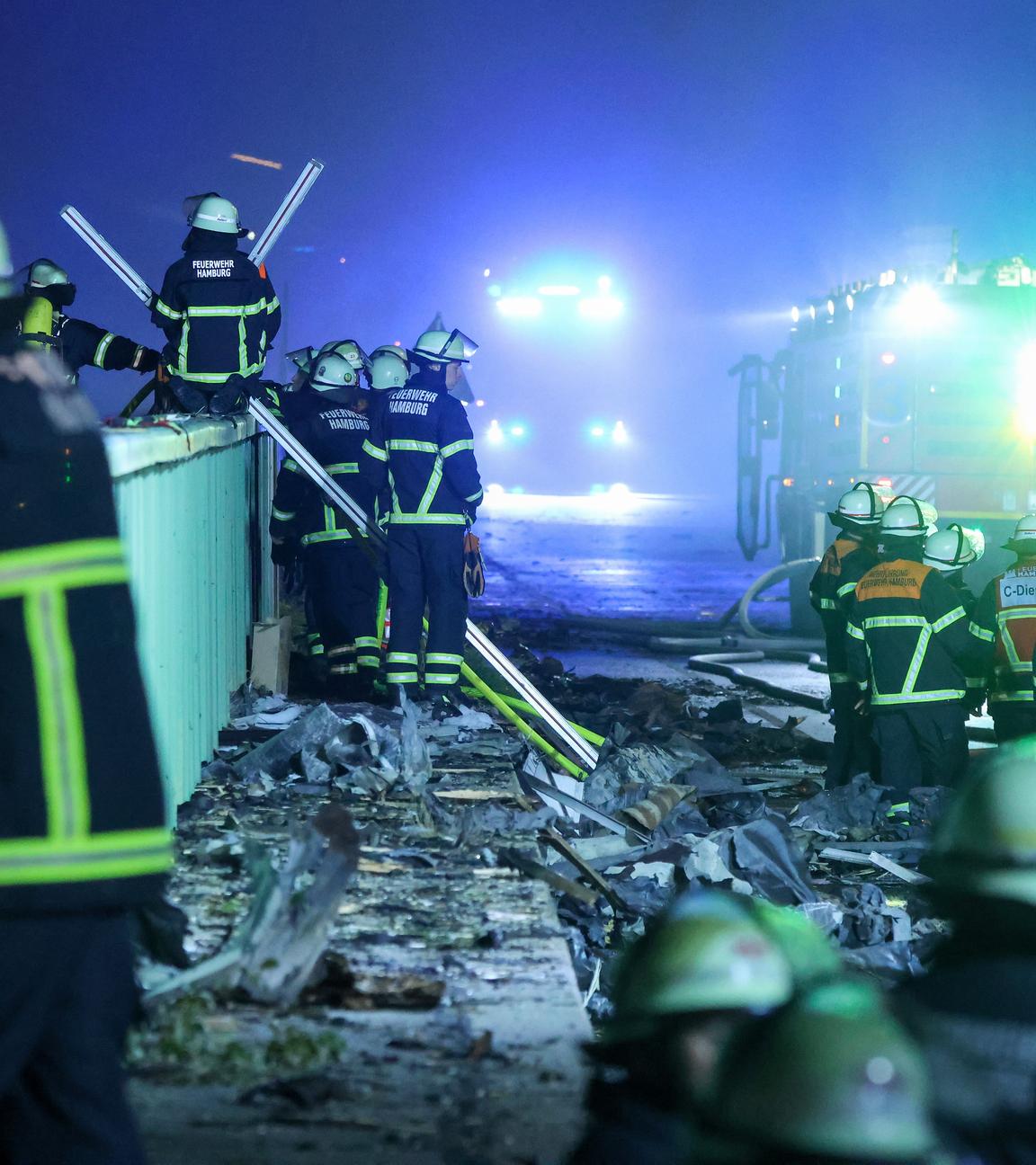 Einsatzkräfte der Feuerwehr sind dabei einen Brand in einem Industriegebiet im Hamburger Hafen zu löschen. 