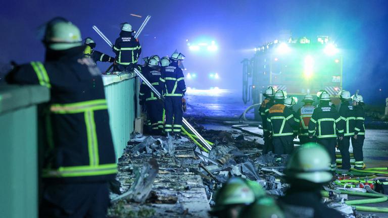 Einsatzkräfte der Feuerwehr sind dabei einen Brand in einem Industriegebiet im Hamburger Hafen zu löschen. 